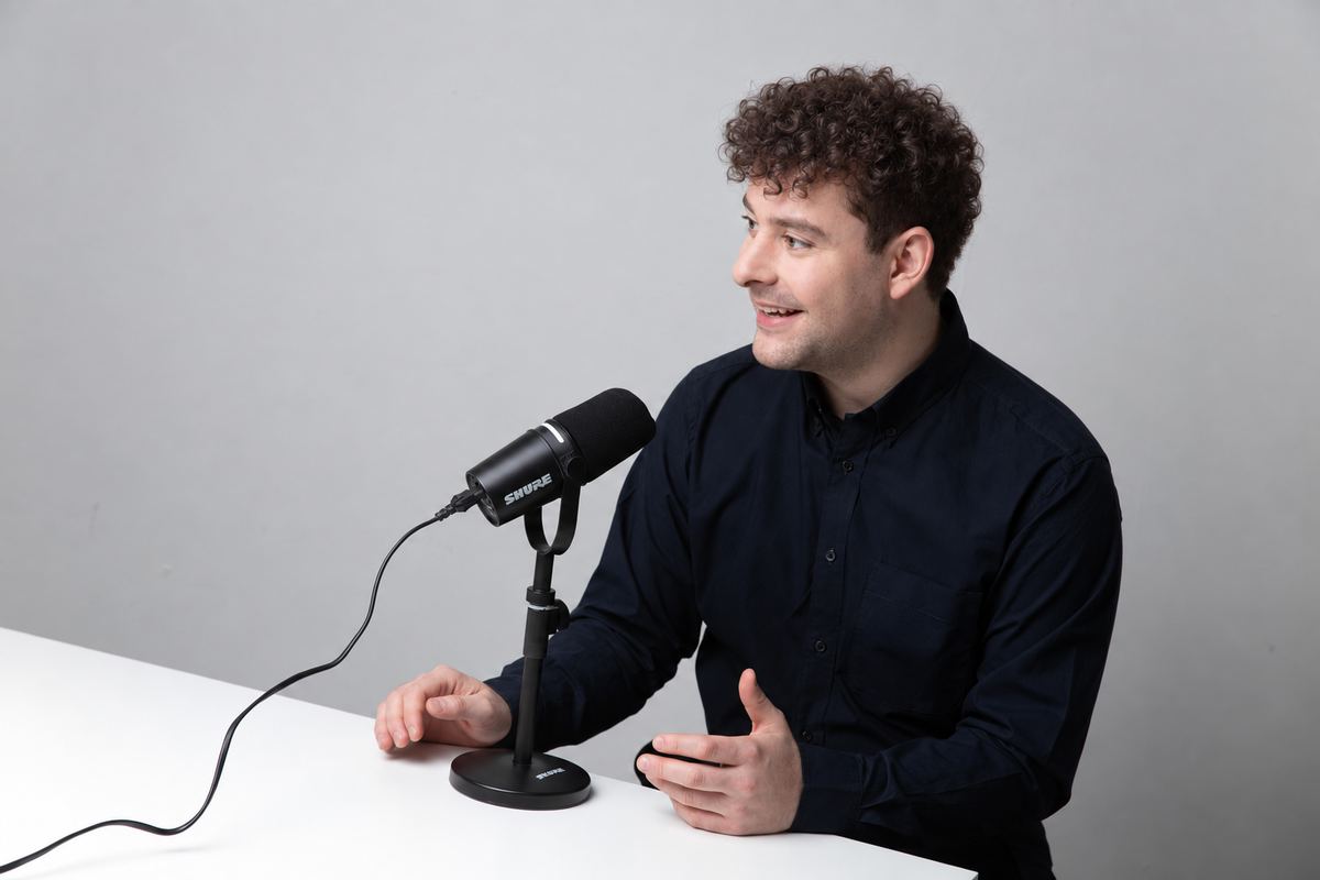 Luca Samlidis spricht am Tisch in ein Podcast-Mikrofon